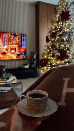 a person holding a coffee cup in front of a christmas tree