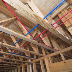 an unfinished room filled with wooden beams and blue piping on the ceiling is being worked on