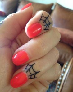 a woman's hand with red nail polish and spider web design on her fingers