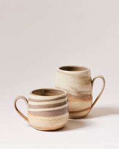 two coffee mugs sitting next to each other