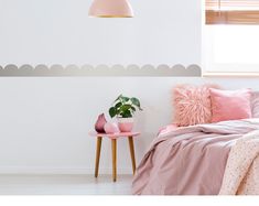 a bed room with a neatly made bed next to a window and a pink chair