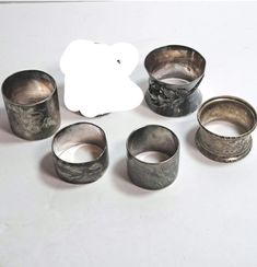 an assortment of silver rings on a white surface