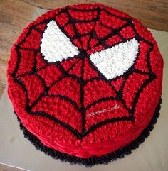 a spiderman cake is decorated with red and white icing