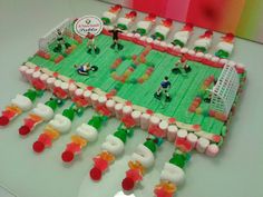 a cake made to look like a soccer field with gummy bears and people on it