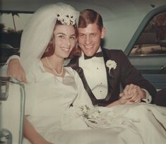 a bride and groom are sitting in the back of a car, smiling at the camera