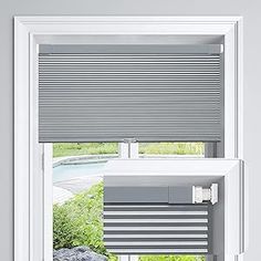 two windows with blinds in the same color as they look out onto a green yard