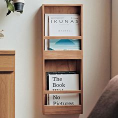 a wooden book shelf with three books on it and a potted plant next to it