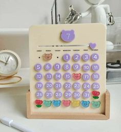 a desk calendar with teddy bears on it and a clock in the back ground behind it