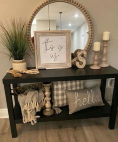 a black console table with pillows and a mirror