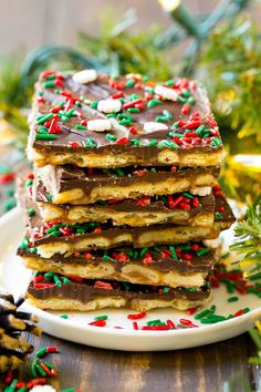 a stack of christmas shortbreads on a plate with sprinkles and chocolate