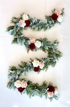 flowers arranged in the shape of letter e on a white surface with greenery and leaves