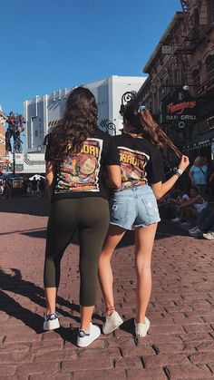 two women are standing on the street with their backs to each other