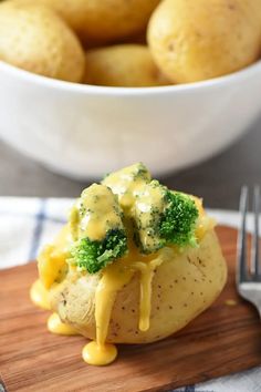 broccoli and cheese stuffed potatoes on a cutting board next to a bowl of potatoes