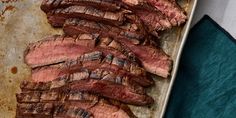 sliced steak on a baking sheet ready to be cooked in the oven, with a blue towel next to it