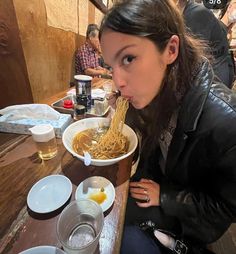 a woman sitting at a table eating noodles