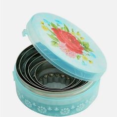 four blue tins with flowers on them sitting next to each other in a box