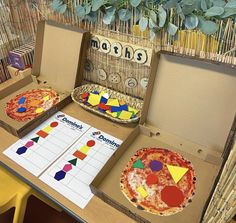 two pizzas in boxes on a table with matching numbers and shapes cut out from them