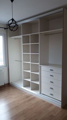 an empty room with white shelves and drawers