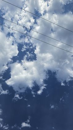 an airplane is flying in the sky with power lines above it and clouds behind it