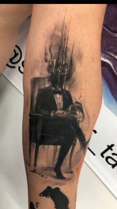 a man's leg with a black and white tattoo on it, which has an image of a person sitting in a chair