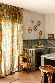 a kitchen with an oven, counter top and window covered in yellow floral drapes