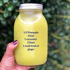 a person holding up a jar of yellow liquid with the words 12 pineapple 4 kiwi 1 cucumber 2 times 1 small nob of ginger