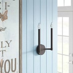 a wall mounted light on the side of a blue painted building with butterfly decals