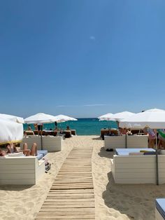 people are lounging on the beach under umbrellas