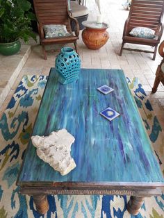 a living room with chairs and a table in the middle on top of a rug