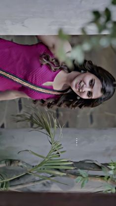 a woman in a pink dress standing next to plants