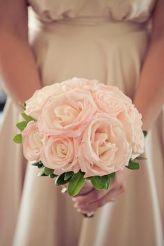 a bride holding a bouquet of pink roses