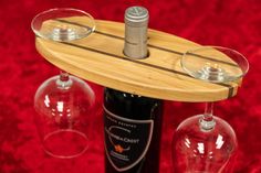 two wine glasses sitting on top of a wooden tray next to a bottle of wine