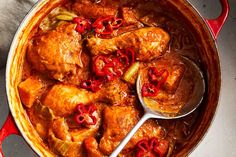 a red pot filled with chicken and peppers