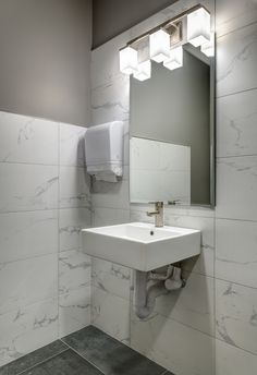 a bathroom with a sink, mirror and towel dispenser on the wall