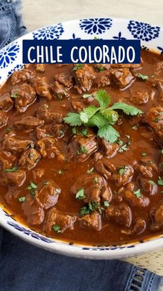 a bowl filled with meat and garnish on top of a blue and white plate