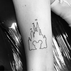 a black and white photo of a castle tattoo on the right arm, with an outline of two people in front of it