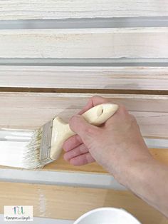 a person using a brush to paint the trim on a window sill with white paint