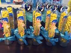 some little tin cans filled with yellow candies next to blue ribbons and candy sticks