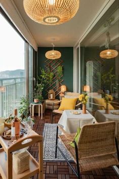 a balcony with wicker chairs, tables and plants on the windowsills are lit by hanging lights