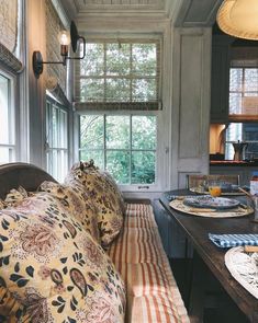 a table with plates and place settings on it in front of a window that looks out onto the woods