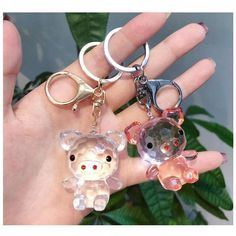 three keychains are shown in the palm of someone's hand, one has a bear and another has a pig