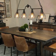 a dining room table and chairs with lights hanging from the ceiling