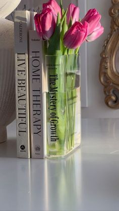 pink flowers are in a vase next to two books