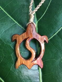 a wooden necklace hanging from a green leaf