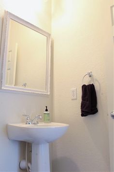 a white sink sitting under a bathroom mirror