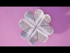 an origami flower made out of money on a pink background