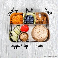 a bento box filled with fruit, veggies and dips on top of a white wooden table