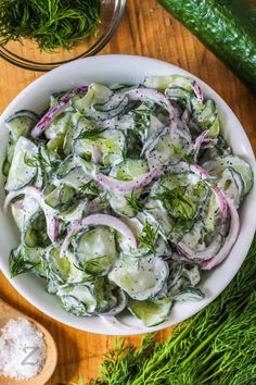 a white bowl filled with cucumbers and onions on top of a wooden table