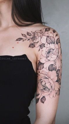 a woman wearing a black dress with flowers on her arm and shoulder tattooing it