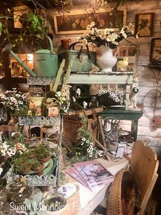 a room filled with lots of plants and pots on top of a white table covered in flowers